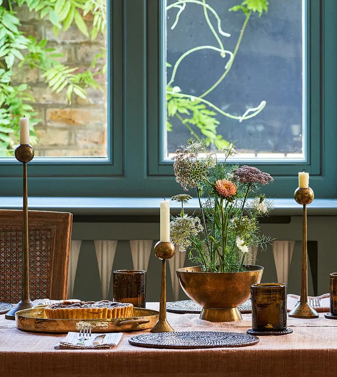 Cosy table is set with Kalinko rattan placemats and brass candle sticks available at The Wedding Present Company