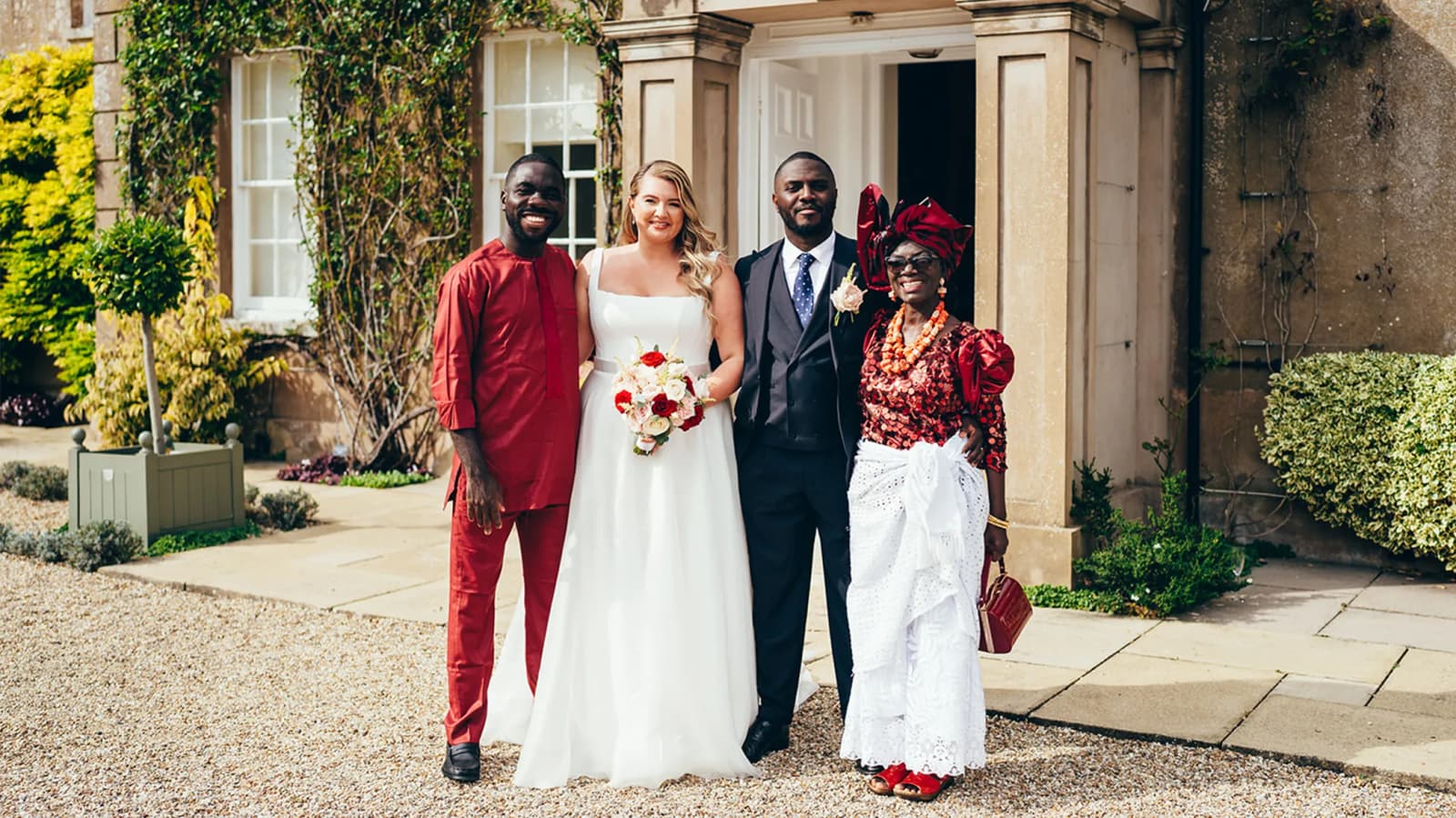 Formal group wedding portrait with bride, groom and groom's family in traditional Nigerian outfits.