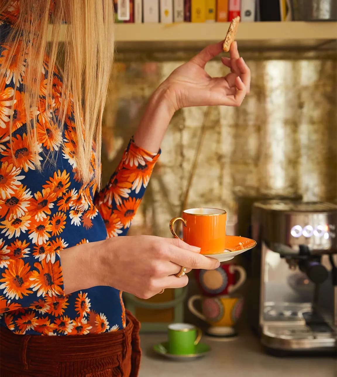 A woman with engagement ring holds her wedding gift, orange coffee cup, in the kitchen