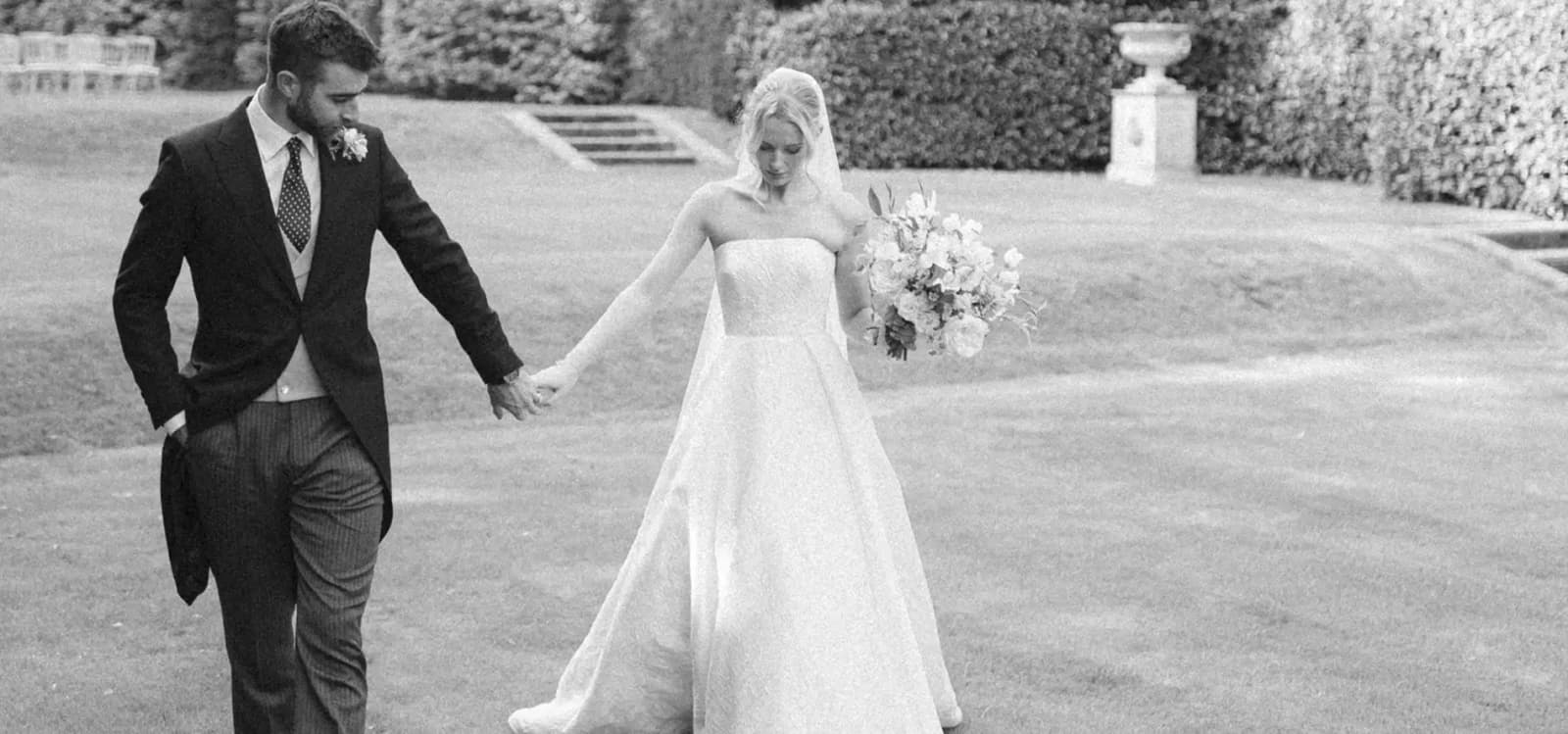 A groom and bride stroll through the garden of their Hampshire country house wedding venue.