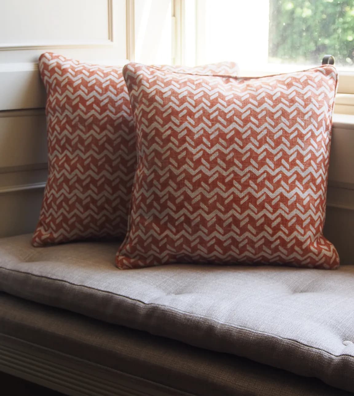Red patterned Fermoie cushions styled on a bay window bench