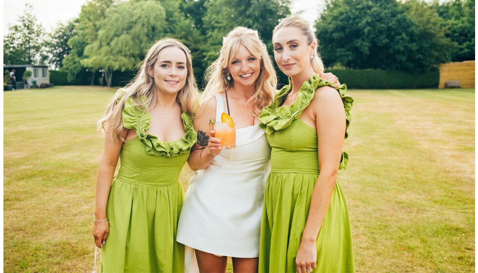 Whimsical Tuscan-Inspired Wedding in Hampshire | Bride in mini white wedding dress, standing next to bridesmaids in ruffled olive green dresses