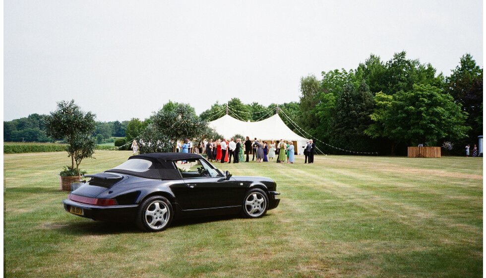 Whimsical Tuscan-Inspired Wedding in Hampshire | A black vintage convertible outside wedding marquee in Hampshire