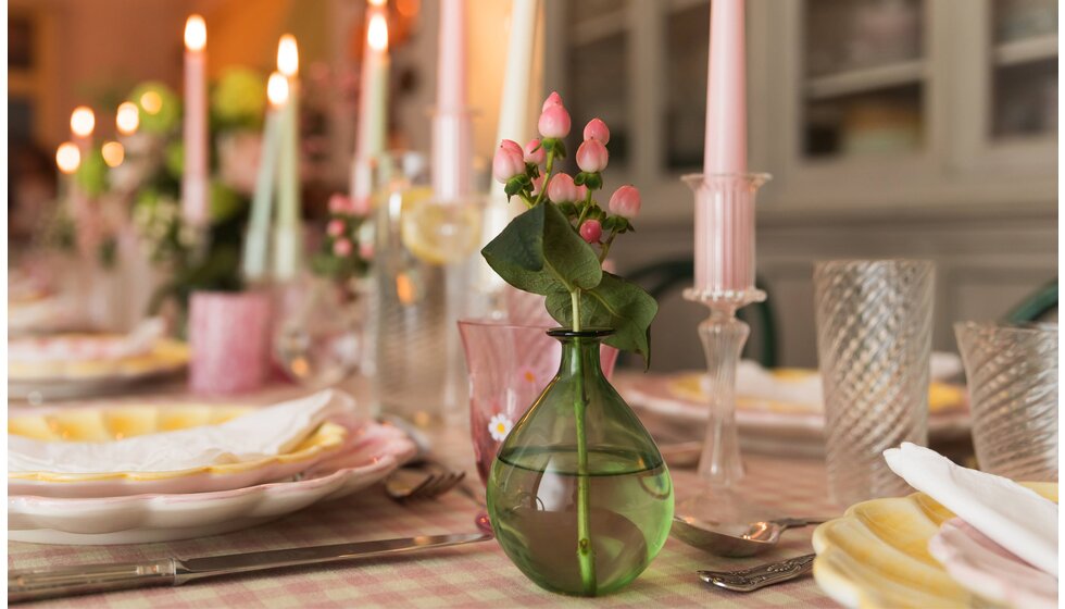 Supper Club with Skye McAlpine | A close-up of the pink and yellow tablescape with candles and a small green vase with flowers