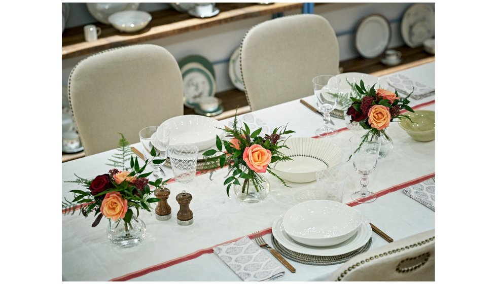 A dining room table laid with table linen, flowers and china.
