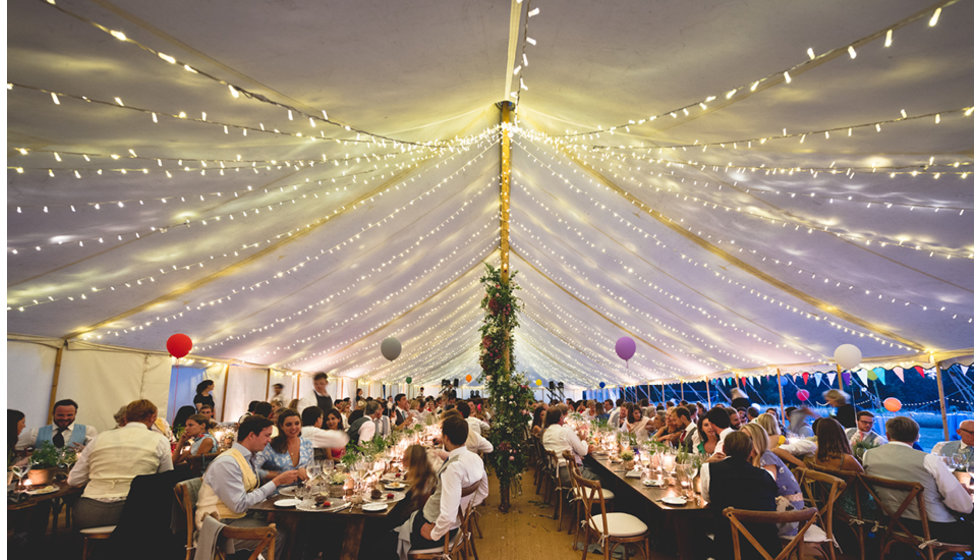 The inside of Daisy and Charlie's marquee at night while guests enjoy dinner