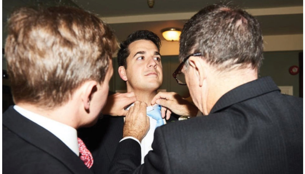 The ushers help Jamie with his tie.