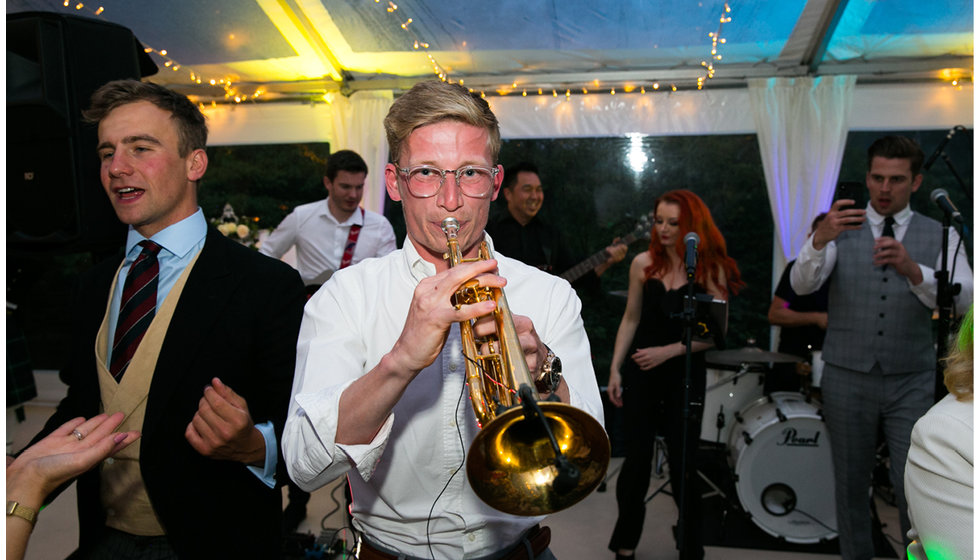 One of the musicians playing the trumpet amongst guests on the dance floor. 