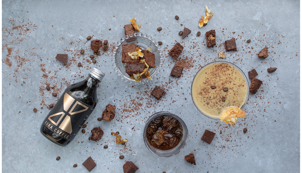 Overhead shot of an Espresso Martini and Salted Chocolate Brownie Bites scattered alongside a bottle of Kuka Coffee Cold Brew.