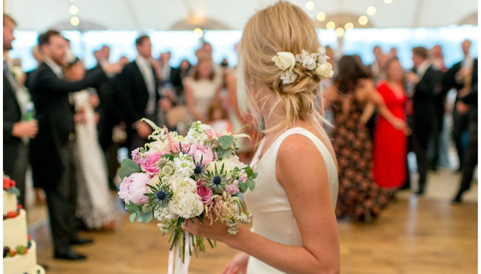 Shot of Jo's updo with roses in her hair holding her bouquet.