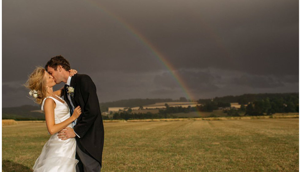 Jo and Sam kiss under a rainbow. 
