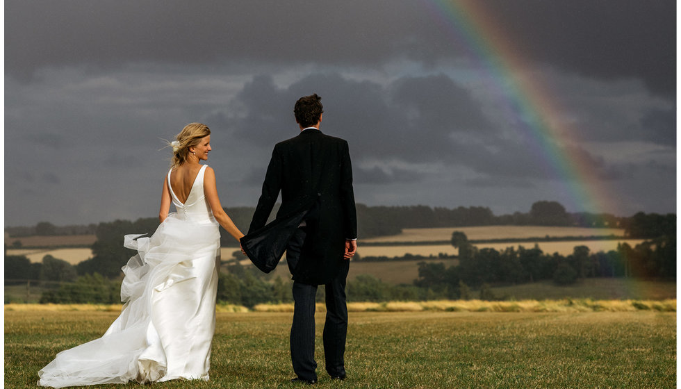 Real couple Jo and Sam under a rainbow on their wedding day