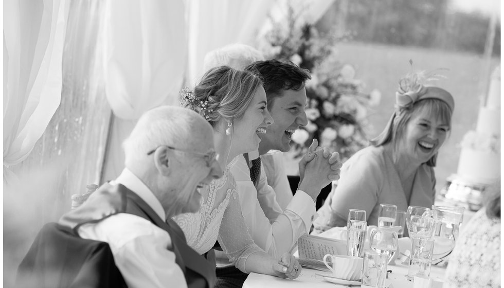 The bridal party laughing during speeches.