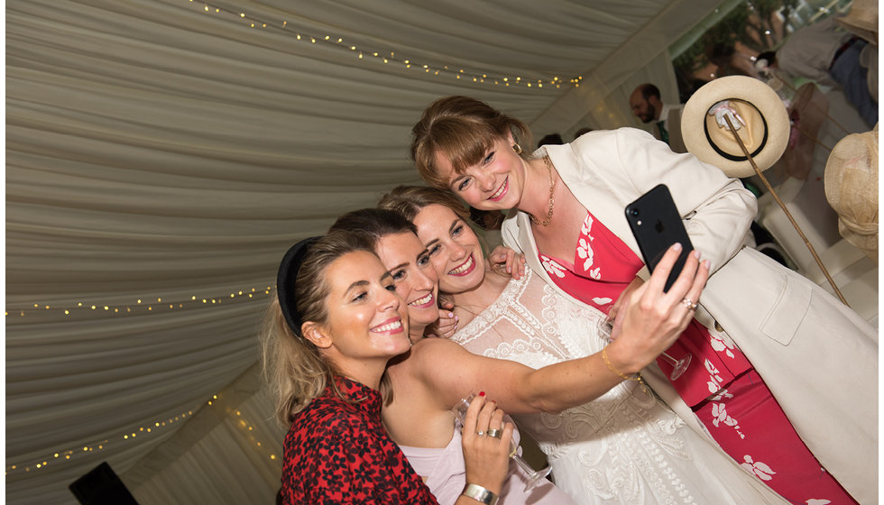 The bride and her guests on the dancefloor taking a selfie.
