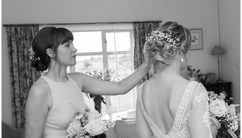 A bridemaid putting the finishing touches on the brides hair.