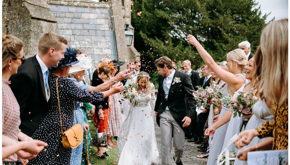 Poppy and Freddie along with their guests throwing confetti over them outside the Church.