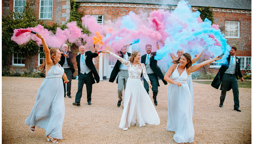 Poppy and members of her wedding party with different blue and pink smoke bombs.