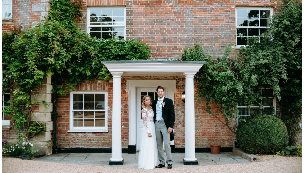 Poppy and Freddie stand outside their wedding venue Syrencot.