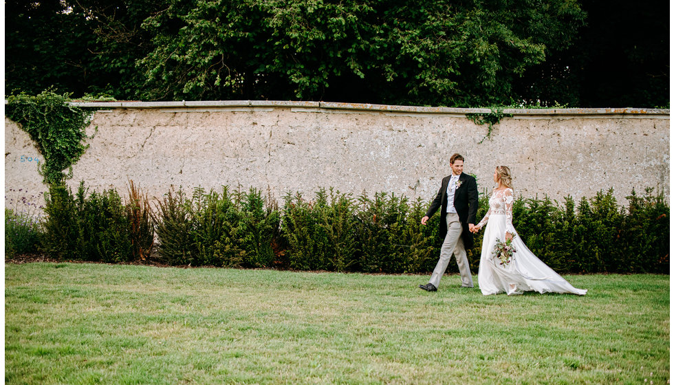 Poppy and Freddie walking through the grounds of their wedding venue.