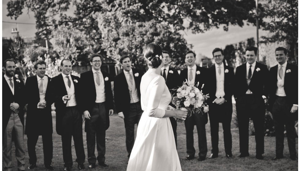 The bride in front of the groomsmen.