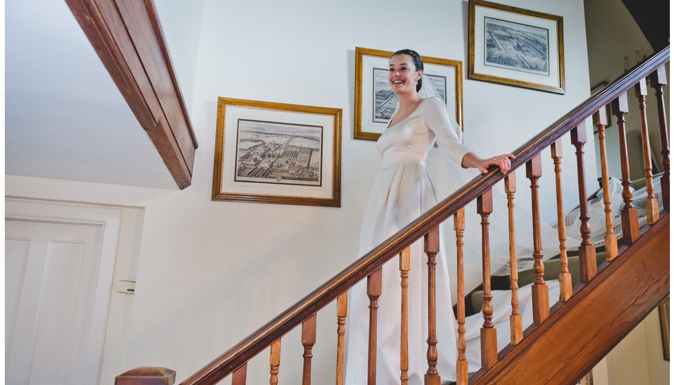 The bride coming down the stairs on her wedding dress.
