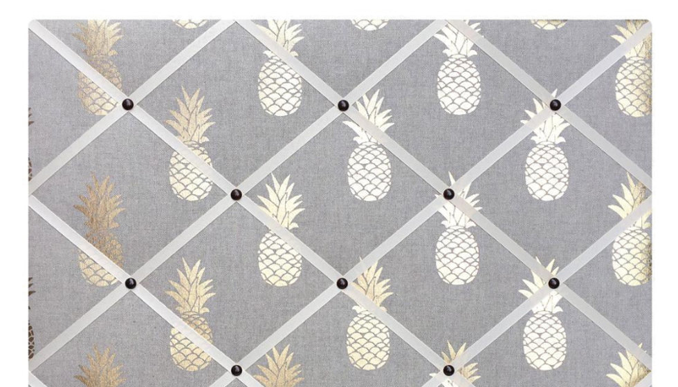 A large gold pineapple fabric notice board with white ribbon.