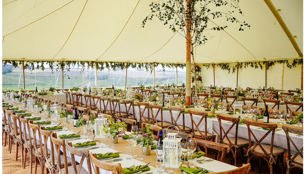 A shot of the inside of the marquee - decorated in flowers and the tables set with lovely white lanterns and green napkins.