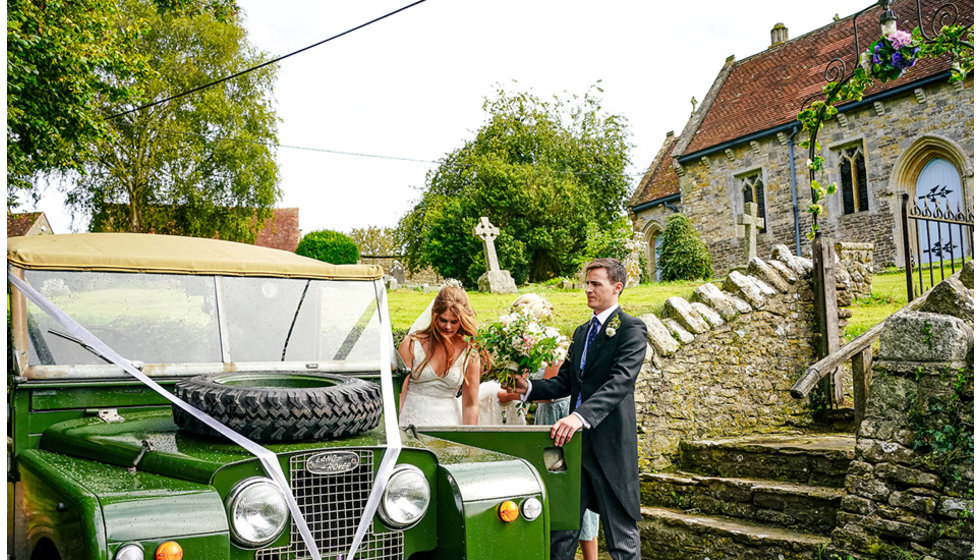 Josh helping Victoria into the decorated landrover outside the church where they got married.