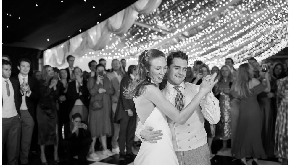 The bride and groom doing their first dance with the ceiling covered in fairy lights in the background. 