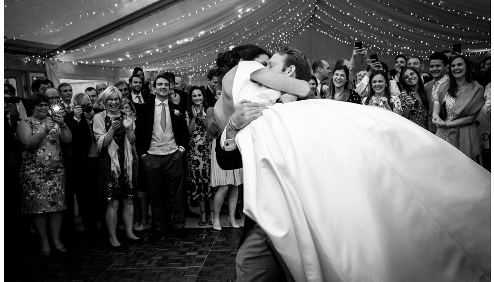 A bride being lifted up by her husband on the dancefloor.