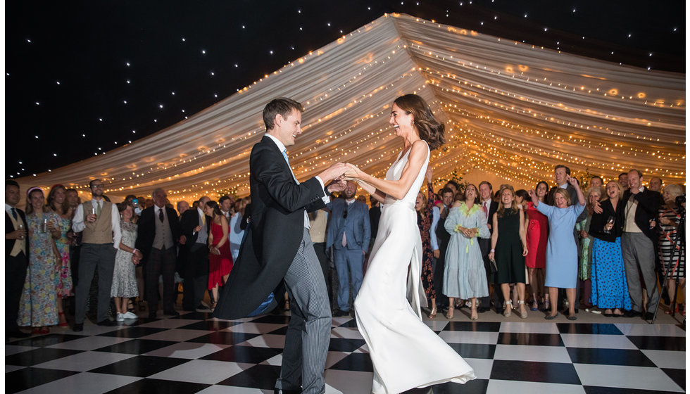Bride and groom doing their first dance on a checkered dancefloor.