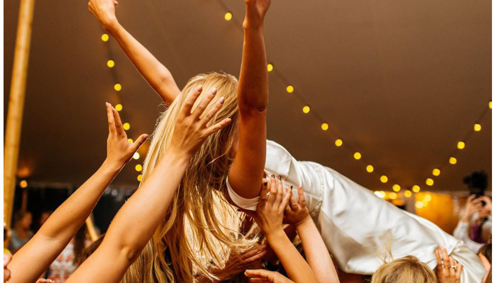 One of the brides crowd surfing in the marquee on her wedding day.