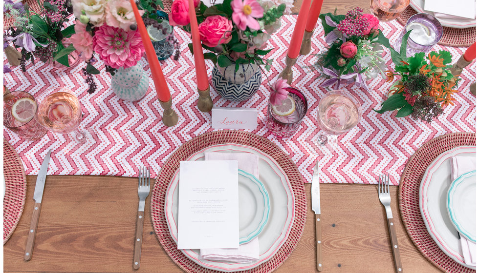Colourful table laid with lots of pinks and fresh flowers.