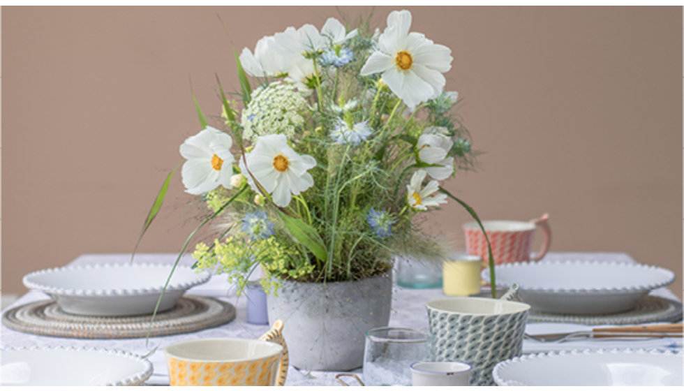 Tablescape with a planter of spring flowers in the middle.