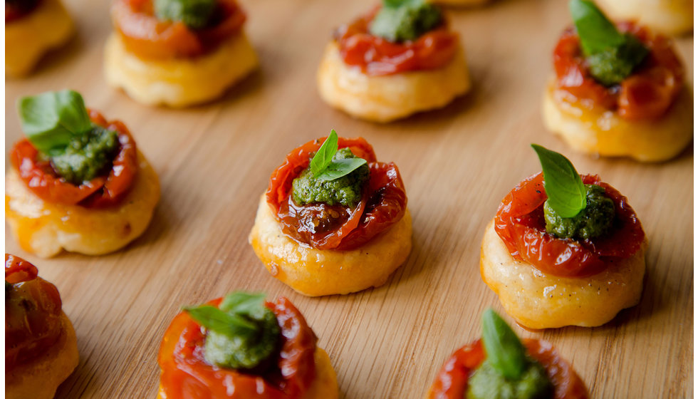A tray of canapés of confit tomato on a small bread.