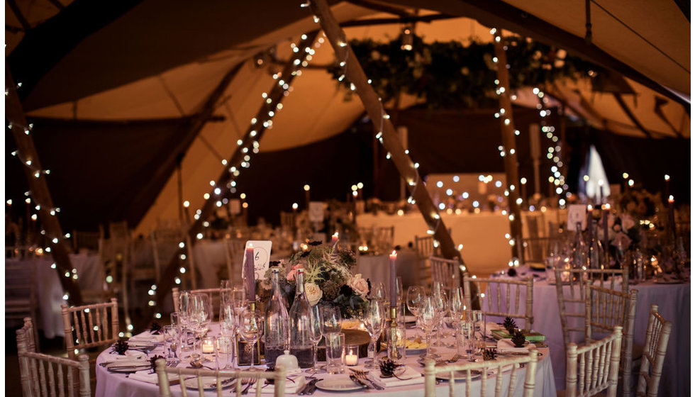 The inside of a marquee lit up by fairy lights.