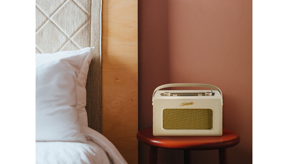 A Roberts radio styled on a bed side table.