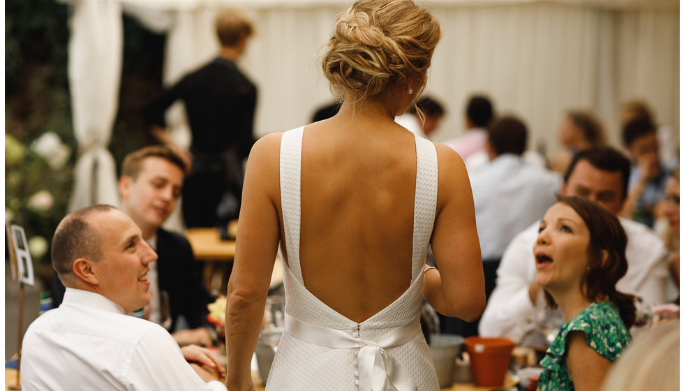 A close up of the brides hair and her backless dress chatting to her guests.