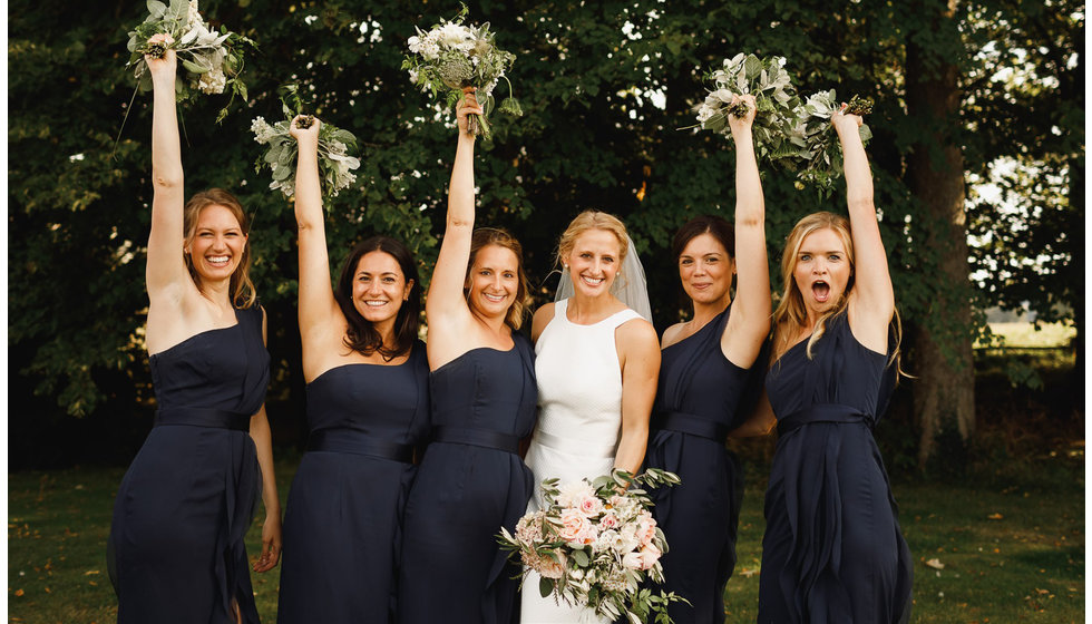 The bridesmaids all lifting their bouquets in the air.