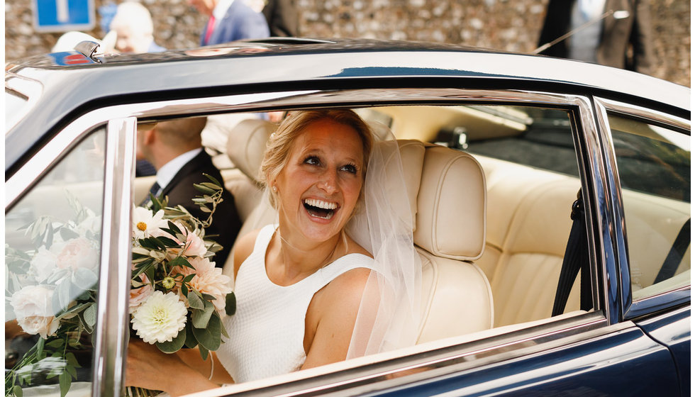 A close up of the bride in a car holding her bouquet.