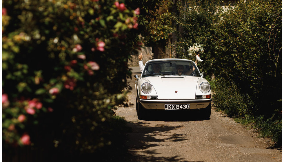 The bride and her father arriving to the church in a white vintage 911.