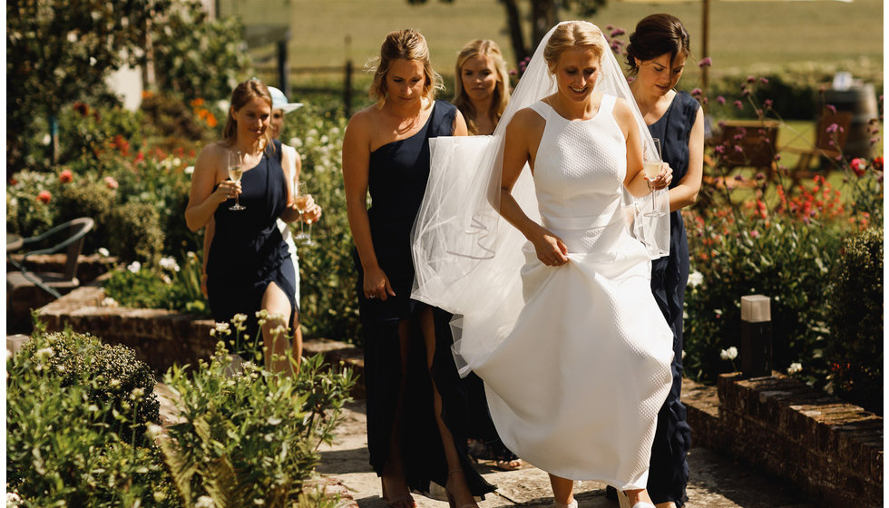 The bride being followed by her bridesmaids all holding a glass of champagne.