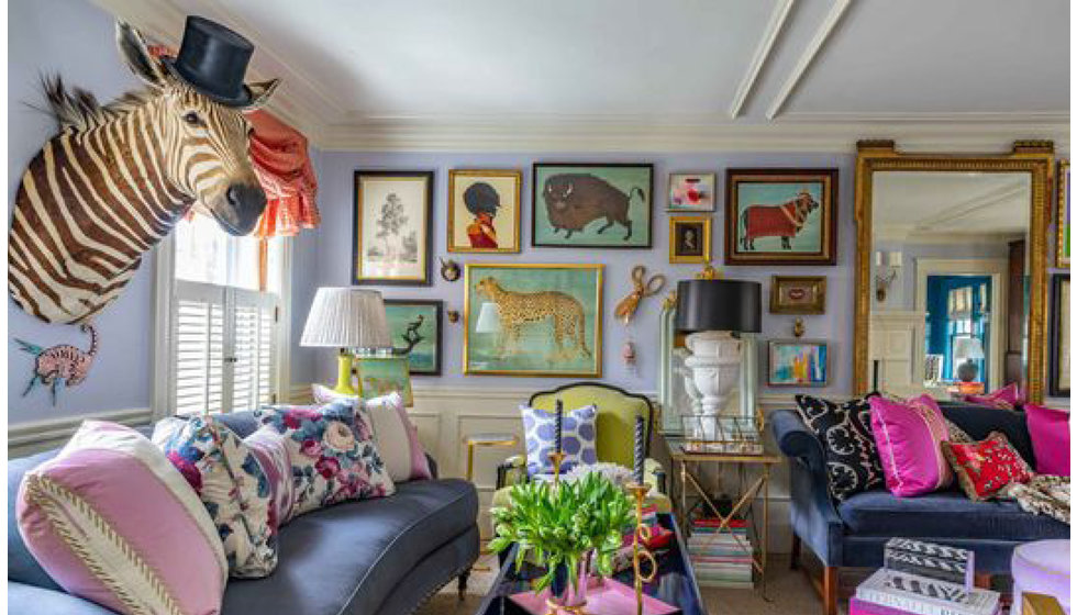 An image of a colourful house with a gallery wall at the back of the room filled with colourful paintings and prints.