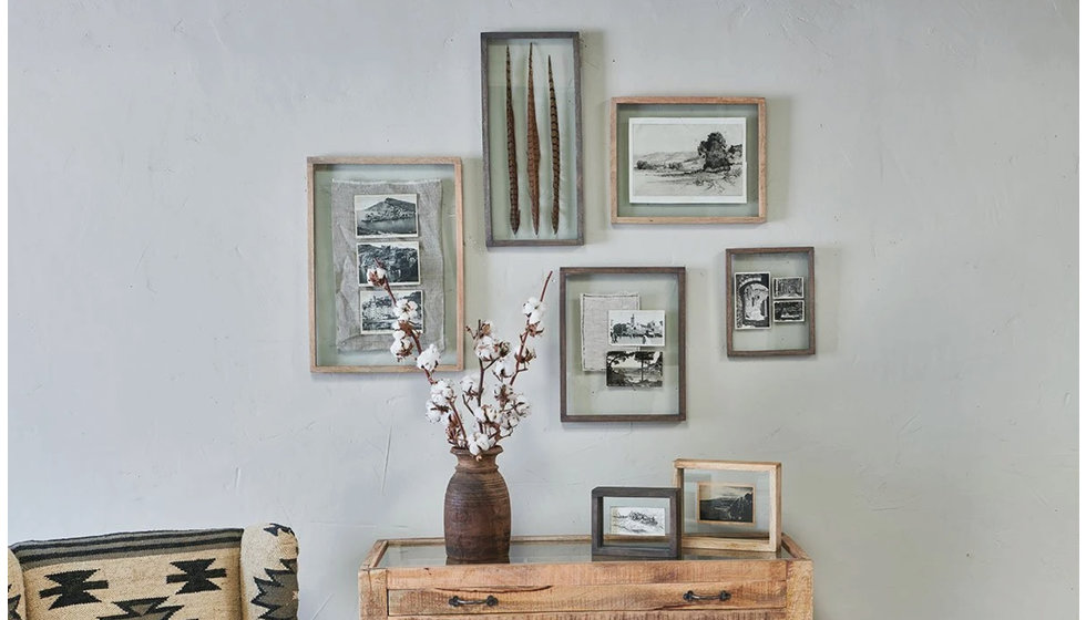 A gallery wall of photographs and framed objects such a pressed flowers and feathers.