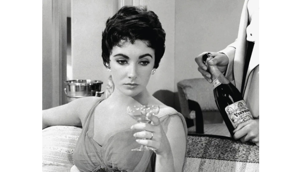 Liz Taylor with coupe of champagne.