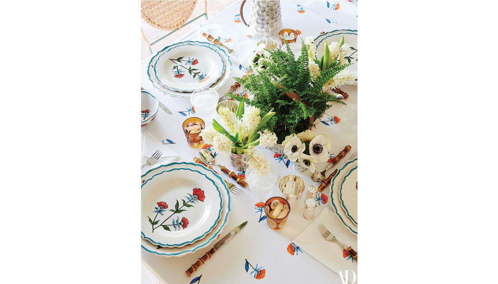 A Spring table made up of a printed tablecloth, bamboo cutlery, scalloped plates and flowers in the centrepiece. 
