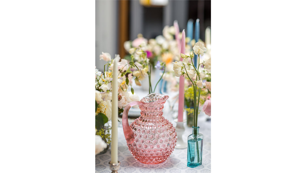 A pink hobnail jug by KLIMCHI is the focal point of this image this antique blue bottles used as vases for the flowers.