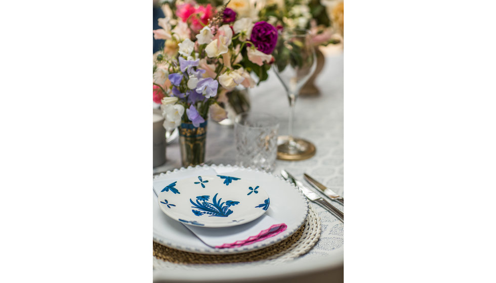 A close up of the table setting with a blue Penny Morrison plate and a pink Sarah K scalloped napkin. Millie Richardson's flowers adorn the table.