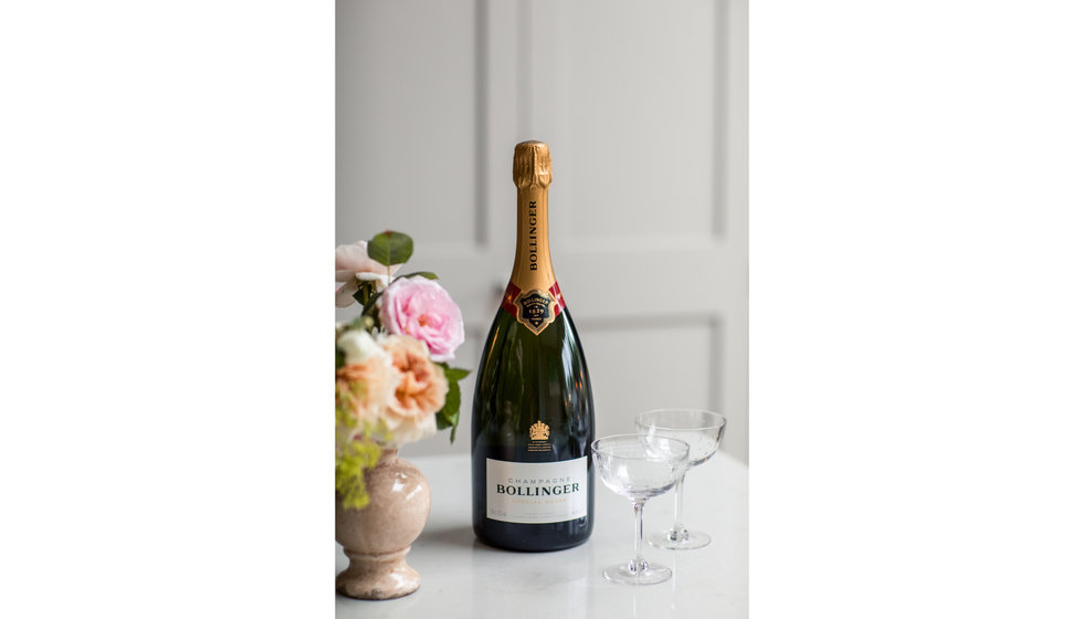 A magnum of Bollinger next to two champagne saucers. 