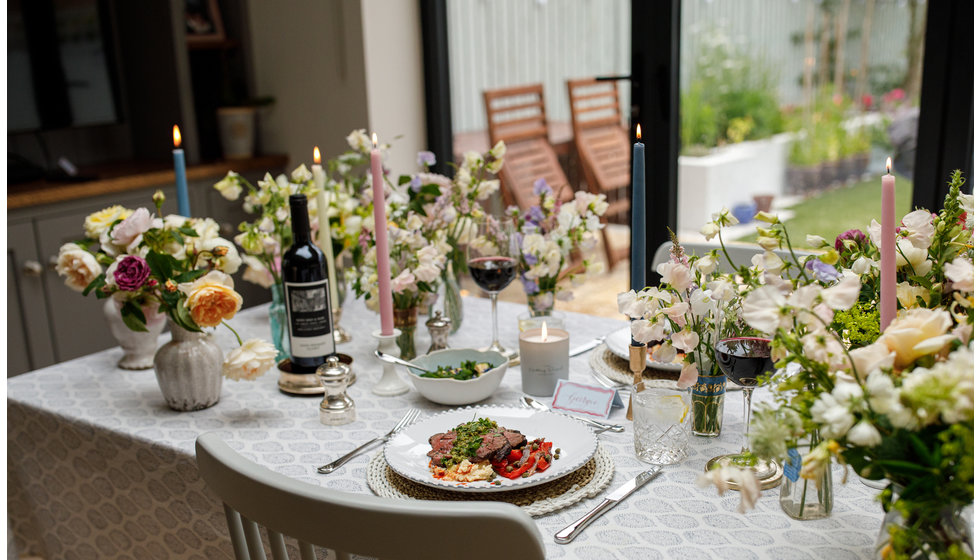 A wide shot of the table as a whole with flowers adorning the table and the main course food laid out.